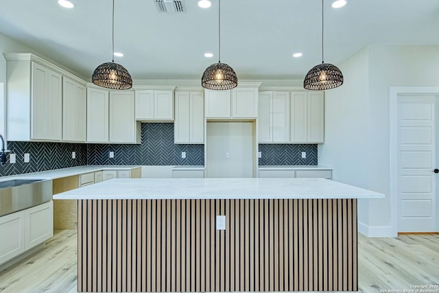 kitchen featuring pendant lighting, white cabinetry, a center island, and light hardwood / wood-style flooring