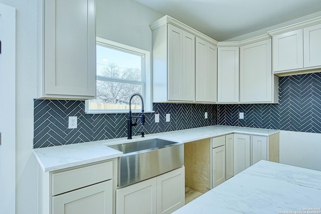 kitchen with light stone countertops, sink, and decorative backsplash