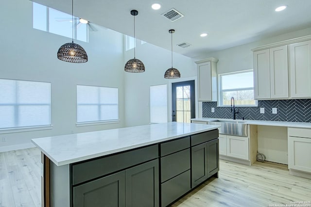 kitchen featuring white cabinetry, sink, decorative backsplash, and light wood-type flooring