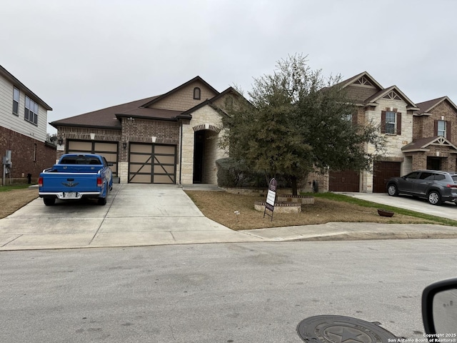 view of front of house with driveway, stone siding, a garage, and brick siding