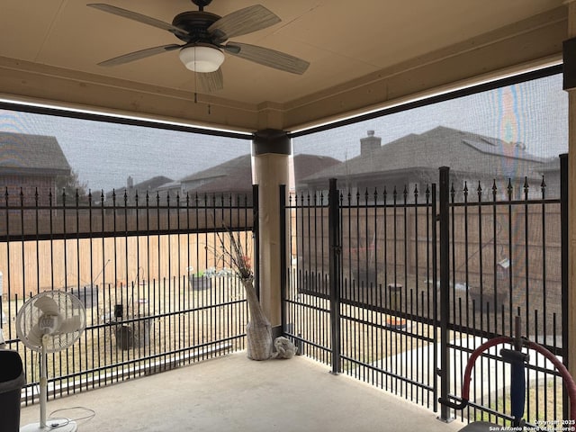 view of gate with fence and a ceiling fan