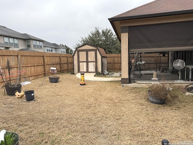 view of yard featuring a shed, a fenced backyard, and an outbuilding