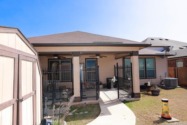 exterior space featuring a shingled roof, a lawn, central AC, fence, and ceiling fan