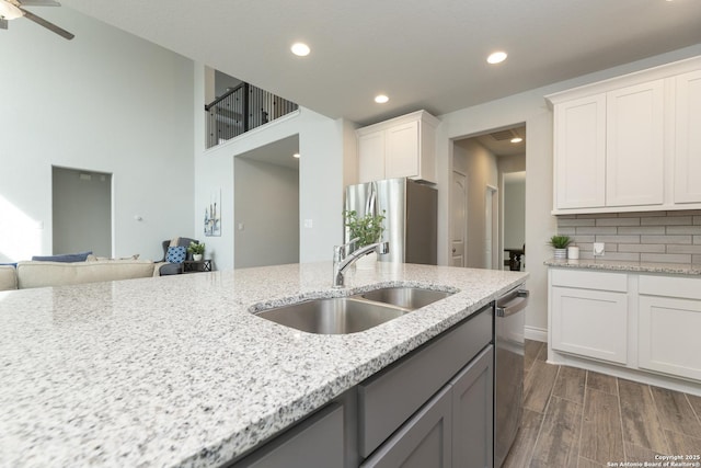 kitchen featuring sink, appliances with stainless steel finishes, white cabinetry, dark hardwood / wood-style floors, and light stone counters