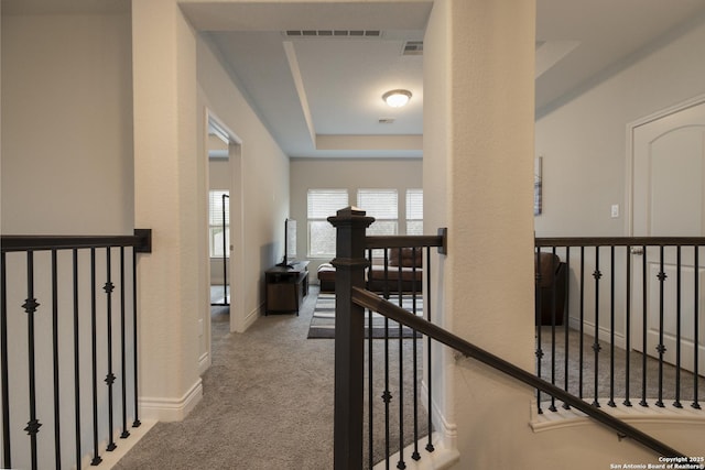 hall featuring light colored carpet and a tray ceiling