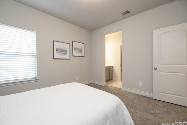 bedroom with connected bathroom and light carpet