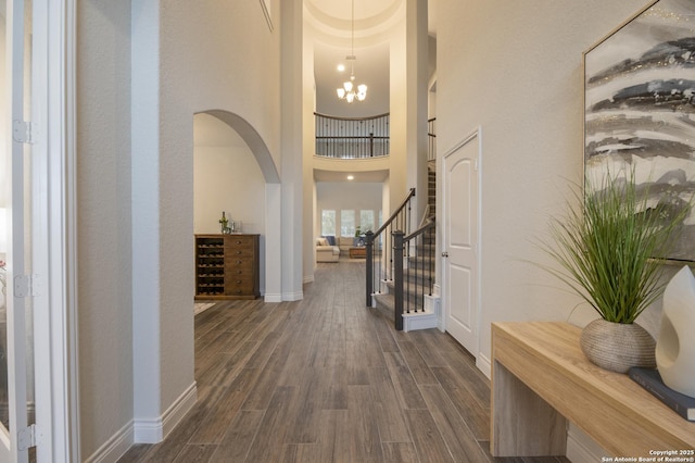 foyer entrance featuring a towering ceiling, dark hardwood / wood-style flooring, and a notable chandelier