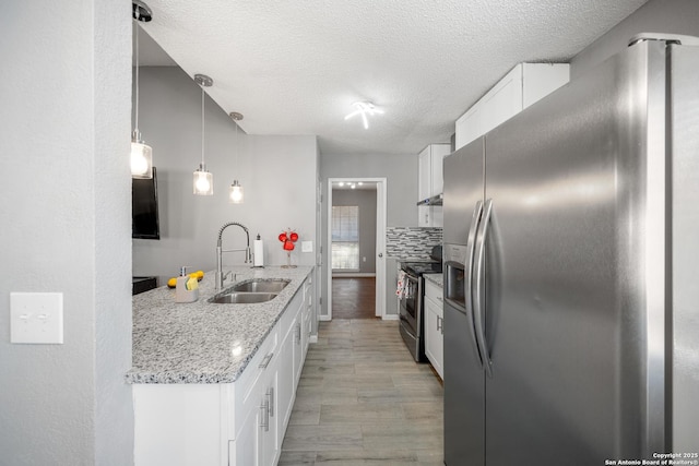 kitchen featuring pendant lighting, sink, stainless steel appliances, light stone countertops, and white cabinets