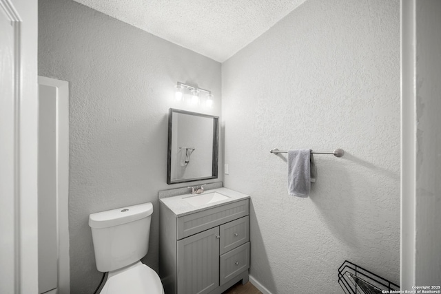 bathroom with vanity, toilet, and a textured ceiling