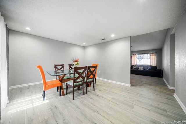 dining room with a textured ceiling and light wood-type flooring