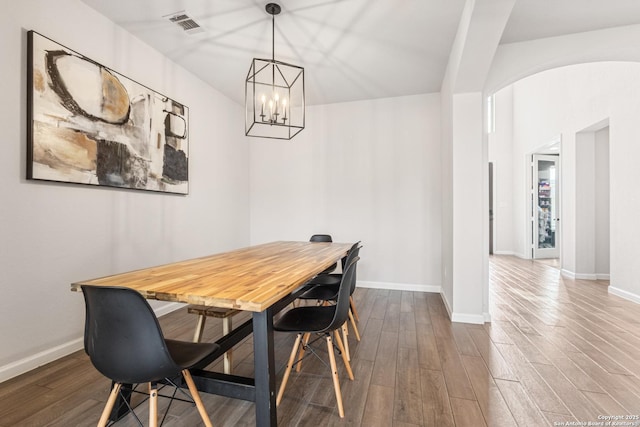 dining space with hardwood / wood-style floors and an inviting chandelier