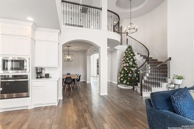 interior space with dark wood-type flooring, an inviting chandelier, and a towering ceiling