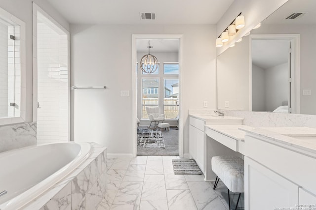 bathroom with an inviting chandelier, vanity, and a relaxing tiled tub