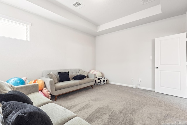 living room featuring carpet flooring and a tray ceiling