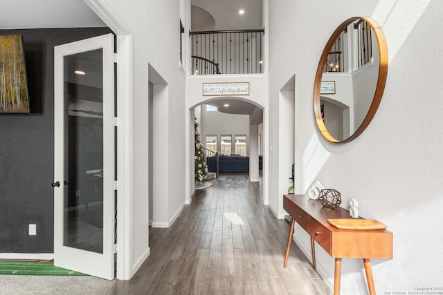 corridor with hardwood / wood-style flooring and a high ceiling