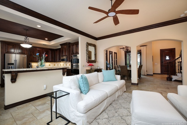 living room featuring ornamental molding, a raised ceiling, and ceiling fan