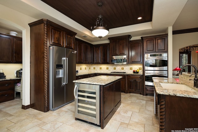 kitchen featuring a kitchen island, appliances with stainless steel finishes, decorative light fixtures, wine cooler, and a tray ceiling