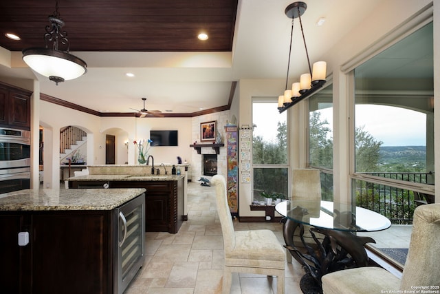 kitchen featuring sink, dark brown cabinets, a kitchen island, decorative light fixtures, and beverage cooler