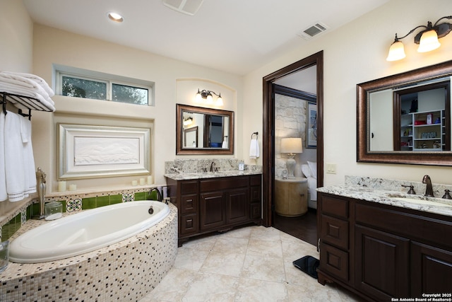 bathroom featuring a relaxing tiled tub, vanity, and tile patterned flooring