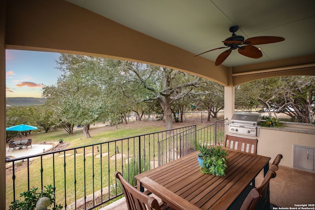 patio terrace at dusk with area for grilling, a yard, and ceiling fan