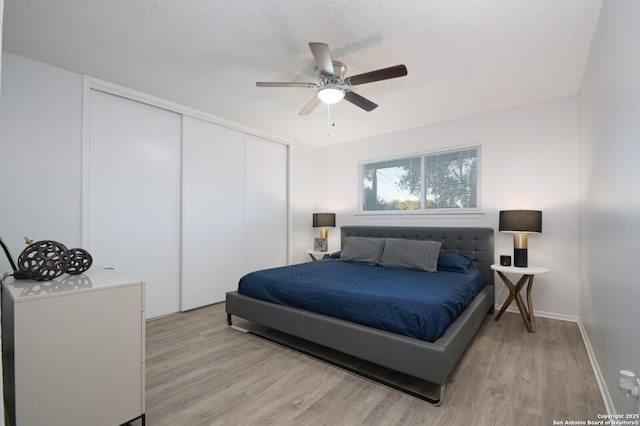 bedroom featuring ceiling fan, light hardwood / wood-style flooring, a textured ceiling, and a closet