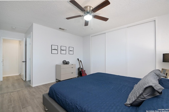 bedroom featuring ceiling fan, a closet, light hardwood / wood-style floors, and a textured ceiling