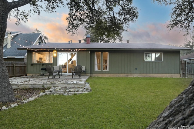 back house at dusk featuring a yard and a patio area