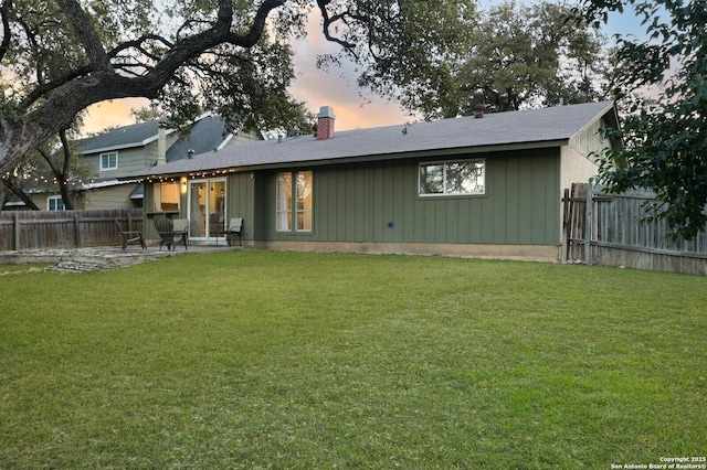 back house at dusk with a lawn