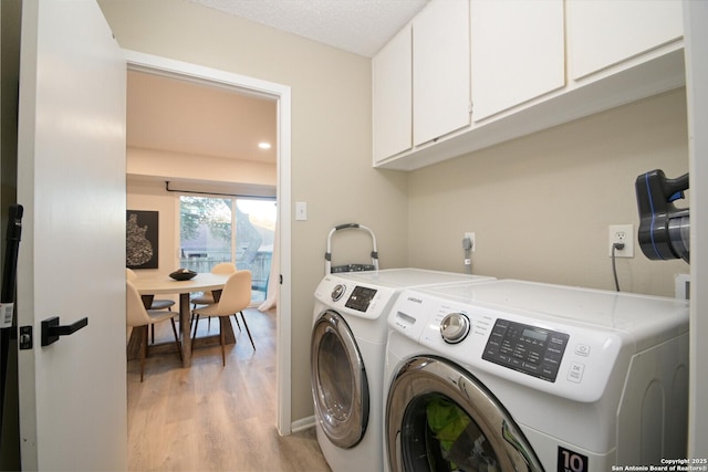 clothes washing area with cabinets, light wood-type flooring, a textured ceiling, and independent washer and dryer