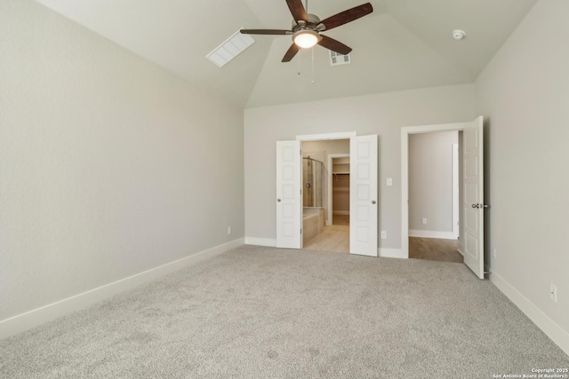 unfurnished bedroom featuring ceiling fan, light colored carpet, vaulted ceiling, and a walk in closet