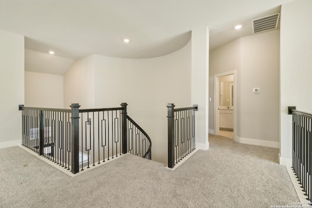 hallway featuring vaulted ceiling and light colored carpet