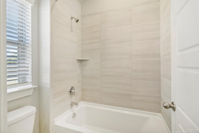 bathroom featuring tiled shower / bath and toilet