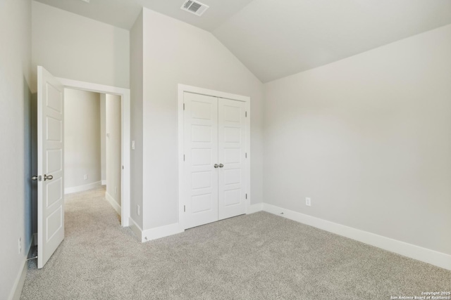 unfurnished bedroom with light colored carpet, lofted ceiling, and a closet