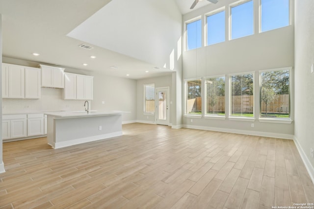 unfurnished living room featuring ceiling fan, sink, and light wood-type flooring