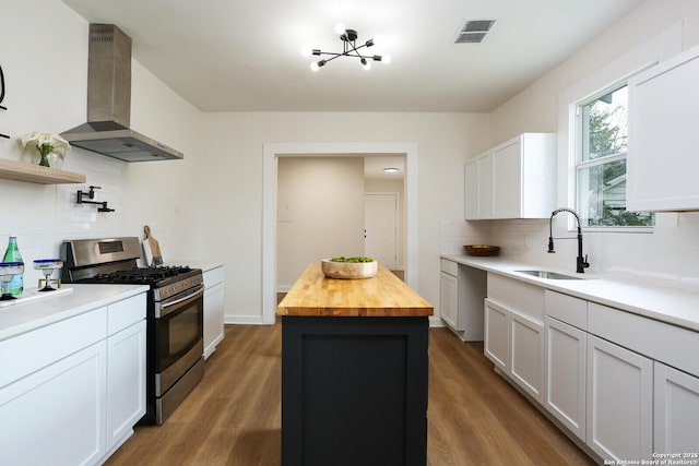 kitchen with white cabinetry, wood counters, stainless steel range with gas stovetop, and exhaust hood