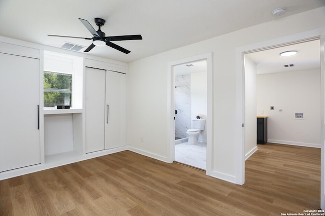 unfurnished bedroom with connected bathroom, wood-type flooring, and ceiling fan