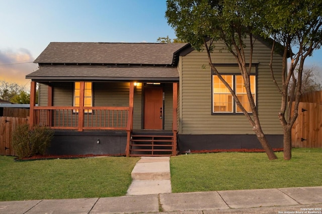 bungalow-style home with a yard and covered porch