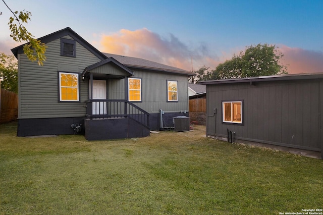 back house at dusk with cooling unit and a yard