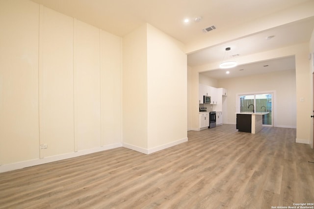 unfurnished living room featuring sink and light wood-type flooring