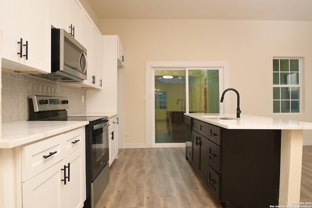 kitchen featuring a kitchen island with sink, sink, white cabinets, and appliances with stainless steel finishes