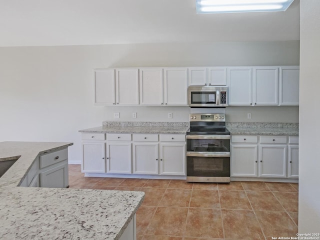 kitchen featuring white cabinetry, stainless steel appliances, light stone counters, and light tile patterned floors