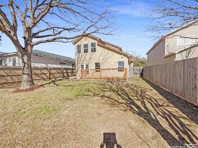 rear view of property featuring a wooden deck and a lawn