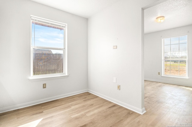 spare room with a textured ceiling and light hardwood / wood-style flooring