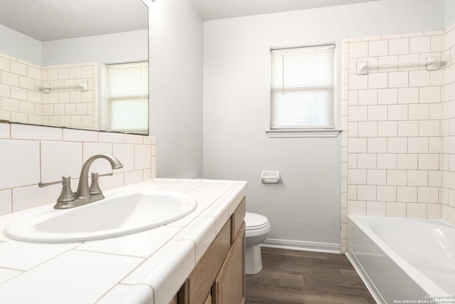 full bathroom featuring toilet, tasteful backsplash, vanity, tiled shower / bath combo, and hardwood / wood-style floors