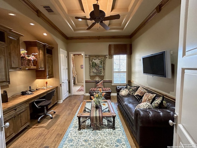 living room featuring crown molding, coffered ceiling, built in desk, and light hardwood / wood-style flooring