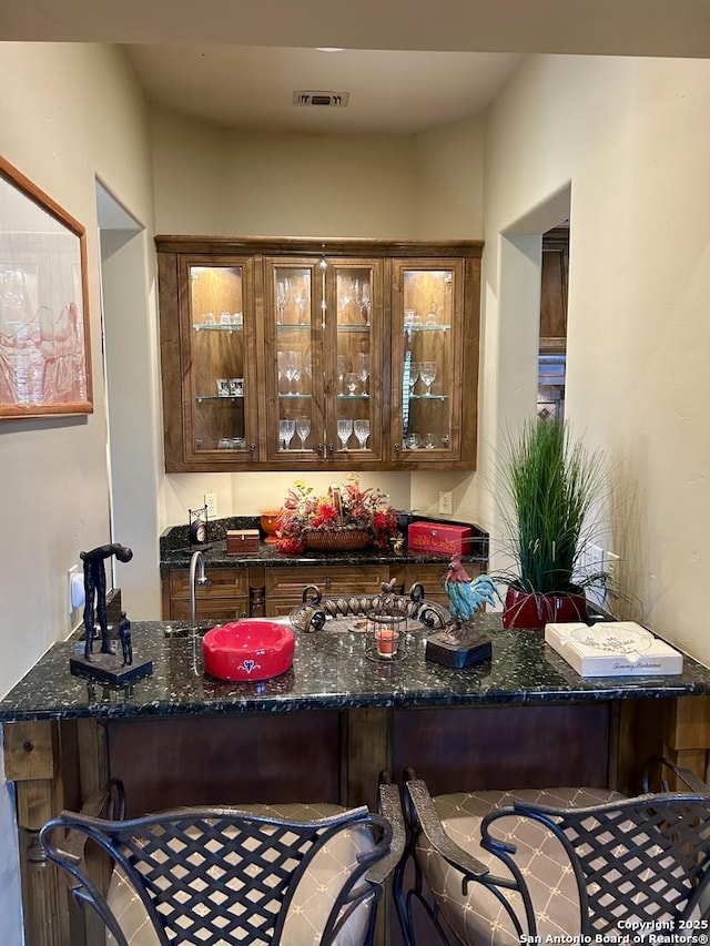 bar featuring dark stone countertops and sink