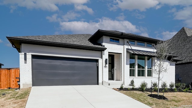 view of front of house with fence, an attached garage, brick siding, and concrete driveway