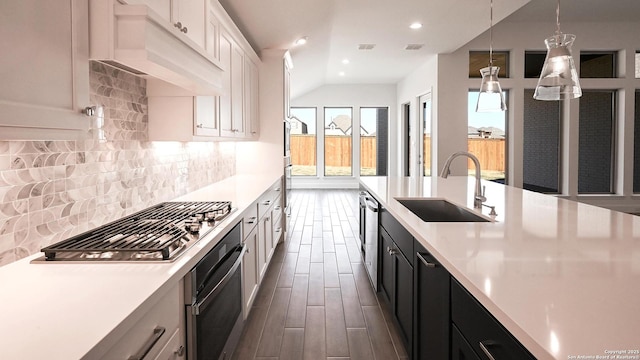 kitchen featuring custom range hood, light countertops, and a sink