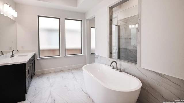 bathroom with vanity, baseboards, a shower stall, a soaking tub, and marble finish floor