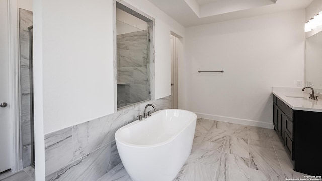full bath featuring marble finish floor, baseboards, a freestanding bath, and vanity